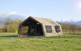 A photograph of the Machu Picchu Khaki inflatable lodge tent on a grassy campsite with mountains in the background.