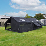 Photo of black military style tent shelter attached to black military style camping tent on grassy campsite with blue sky